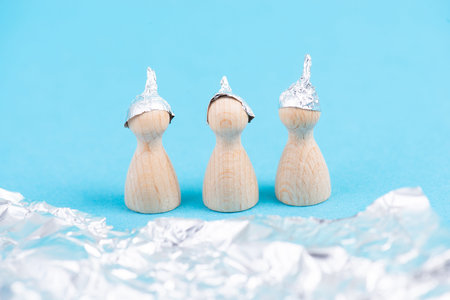 Three wooden figures wearing an alu hat, conspiracy theories, tin foil, symbolic