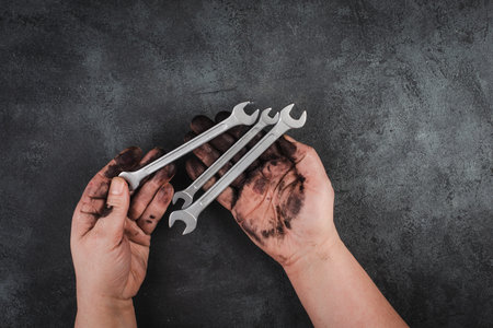 Holding wrench tools in the hands covered with fuel oil, repairing tools, industrial worker, copy spaceの写真素材