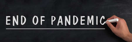 The words end of pandemic are standing on a chalkboard, stop of covid-19 regulations in progress, back to normalの写真素材