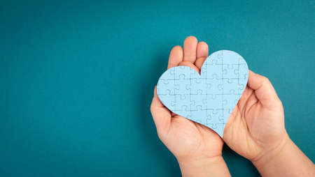 International autism day, hands hold puzzle in the shape of a heart, asperges awareness, psychology, valentine's dayの写真素材