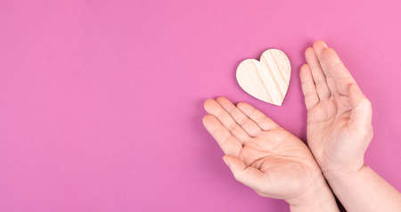 Woman is holding a heart in her hand, pink colored background, copy space, love and charity symbol, hope conceptの写真素材