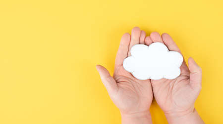 Holding a white cloud in the hand, empty copy space for text, yellow background, communication and marketing concept, being connected, networkingの写真素材