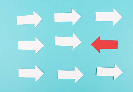 White arrows on a blue background, one red is standing out, do different, be a winner, individuality, making your own decision, leadership, target new ideaの写真素材