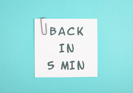 Back in 5 min is standing on a paper, hands hold message, working break, be right back