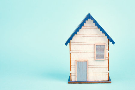 Wooden house, blue background, buying or renting a house, real estate concept, booking home for...