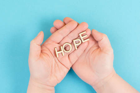 Holding the word hope in the palm of the hands, trust and believe concept, having faith in the future, hopeful positive mindsetの写真素材