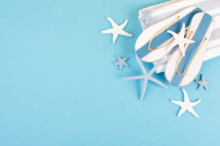 Blue colored summer and vacation background, slippers and sea stars building a frame, copy space for text, holiday and tourism conceptの写真素材