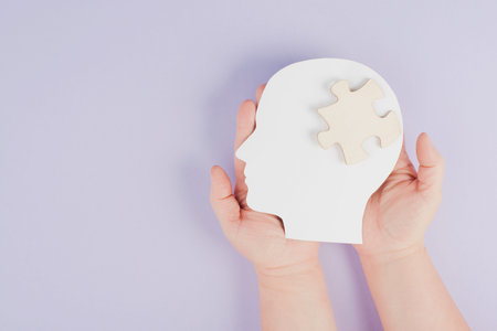 Holding a head with a puzzle piece, mental disease like autism, Alzheimer's, stroke awareness,...