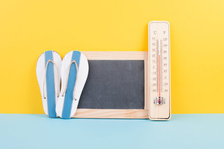 Empty chalkboard with a thermometer and flip flops, holiday background, summer vacation, hot...