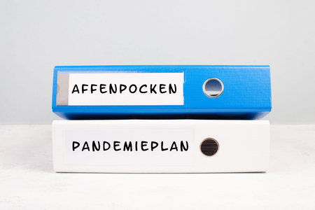 The words monkeypox and pandemic plan are standing in German language on a folder, outbreak of the...