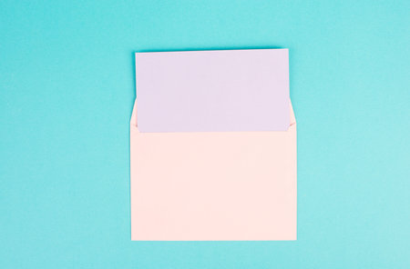 Pink colored envelope with an empty with paper on a turquoise background, copy space for text,...
