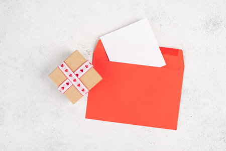Red envelope with an empty paper, gift box with hearts, textured background, birthday, mothers day, fathers day and valentines day greeting cardの写真素材