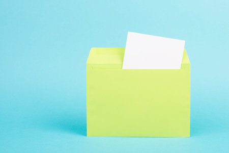 Green colored envelope with an empty with paper on a turquoise background, copy space for text,...