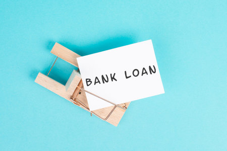 Paper with the words bank loan in a mousetrap, financial debt, inflation, risky credit and...