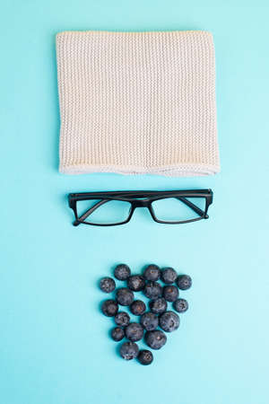 Human face made with a wool hat, glasses and blueberries as a beard, funny minimalist portrait, eco freak lifestyle, vegan foodの写真素材