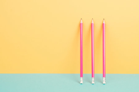 Pink pencils on a yellow and blue background, minimalism, creative, surreal and education concept, copy space for text, pastel colored wallの写真素材
