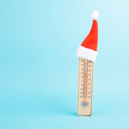 Thermomter with a cute red christmas hat, blue background, copy space for text, greeting card for holiday, winter seasonの写真素材