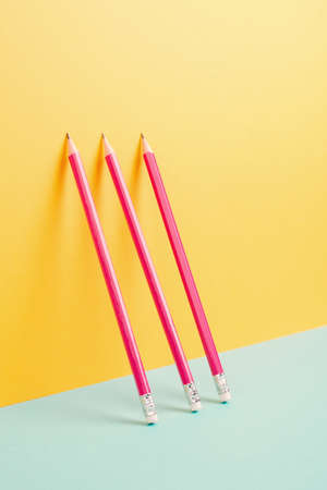 Pink pencils on a yellow and blue background, minimalism, creative, surreal and education concept, copy space for text, pastel colored wallの写真素材