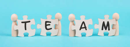 The word team is standing on puzzle pieces, connect the parts together, corporate in teamwork, communication and support conceptの写真素材