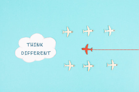 Group of airplanes flying, red plane thinks different and takes the opposite direction, against the...