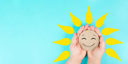 Holding a smiling face with yellow petals in the hands, mental health concept, positive mindset, support and evaluation symbolの写真素材
