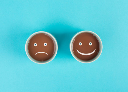 Cup of coffee with a sad and a happy face, positive and negative mindset, support and evaluation concept, emotionの写真素材