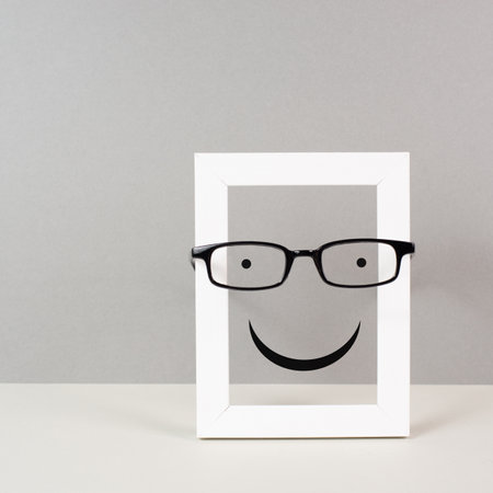 Frame with a happy face with eyeglasses, mental health concept, positive mindset and emotion, support and evaluation symbolの写真素材