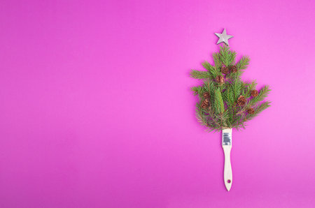 Christmas tree made from fir branches, pine cones and a painting brush as the trunk, pink greeting card with copy spaceの写真素材