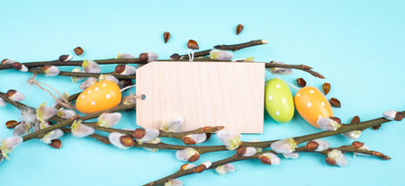 Easter holiday greeting, small colored eggs, branches of pussy willow and a blank tag, spring season