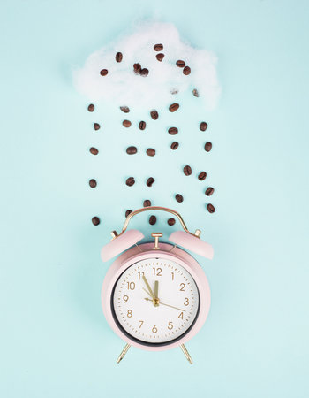 Wake up, time for a coffee break, alarm clock with roasted beans raining from a cloudの写真素材