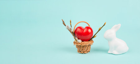 Wicker basket with a big red heart and an easter bunny, rabbit brings gift of love, greeting card for holidayの写真素材