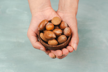 Holding a bowl of nuts, mix variety of almonds, hazelnuts and pecan nuts, healthy food and lifestyleの写真素材