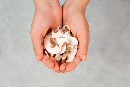 Handful of sliced champignon mushrooms, prepare salad, healthy food with vegetables, fresh organic nutrition, cooking ingredientの写真素材
