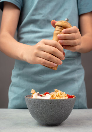 Putting pepper in a pasta salad, sliced mushroom, tomato, red pepper pieces and tuna, healthy food...