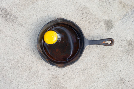 Raw egg in a frying pan on the hot asphalt road, fried food on the sidewalk, hot weather concept,...