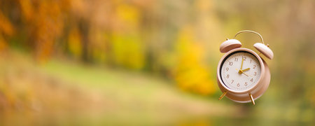 Alarm clock with autumn foliage, end of daylight saving time in fall, winter time changeoverの写真素材