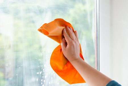 Employee cleaning window pane, wipe with a cloth, dry the water and soap, swab dusty and dirty...