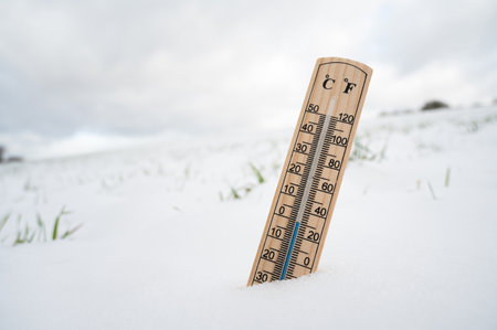 Thermometer in snow covered landscape, cold frosty weather forecast in winter, measure the temperatureの写真素材