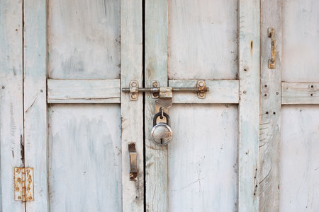 Old weathered door locked with a padlock, white shabby color, Indiaの写真素材