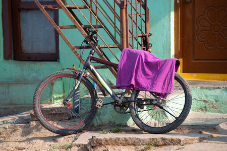 Old bicycle with a towel in front of a house in India, transportation, environmental conversationの写真素材