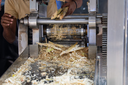 Sugarcane juicing machine on a market stall in India, fresh pressed juice from stalks, squeeze the...