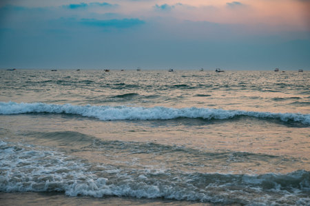 Sunset at Colva Goa beach in South India, silhouette of boats, tropical west coast, Arabian Sea in...