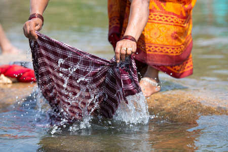 Indian woman washing clothes at Tungabhadra river, Hampi, colorful fabrics, traditional bangles on arm, lifestyle and culture of Indiaの写真素材