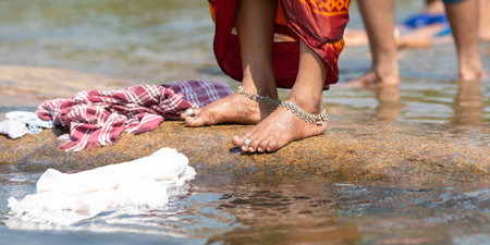 Indian woman washing clothes at Tungabhadra river, Hampi, colorful fabrics, traditional bangles on...