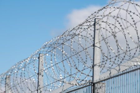 Barbed wire, border control, illegal immigration and migration, refugee camp, prison fence, coils of razor wires, protection and security conceptの写真素材