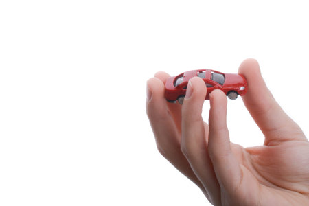 Child's hand holding a red car on a white backgroundの写真素材