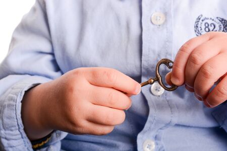 Baby with a blue shirt holding a  metal key in his hand  on a white backgroundの写真素材
