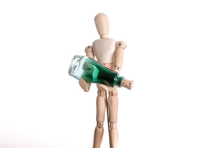 Wooden man holding a green bottle on white backgroundの写真素材