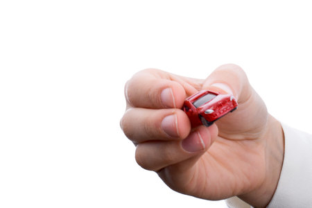 Child's hand holding a red car on a white backgroundの写真素材