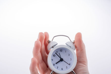 Alarm clock in hand on a white background